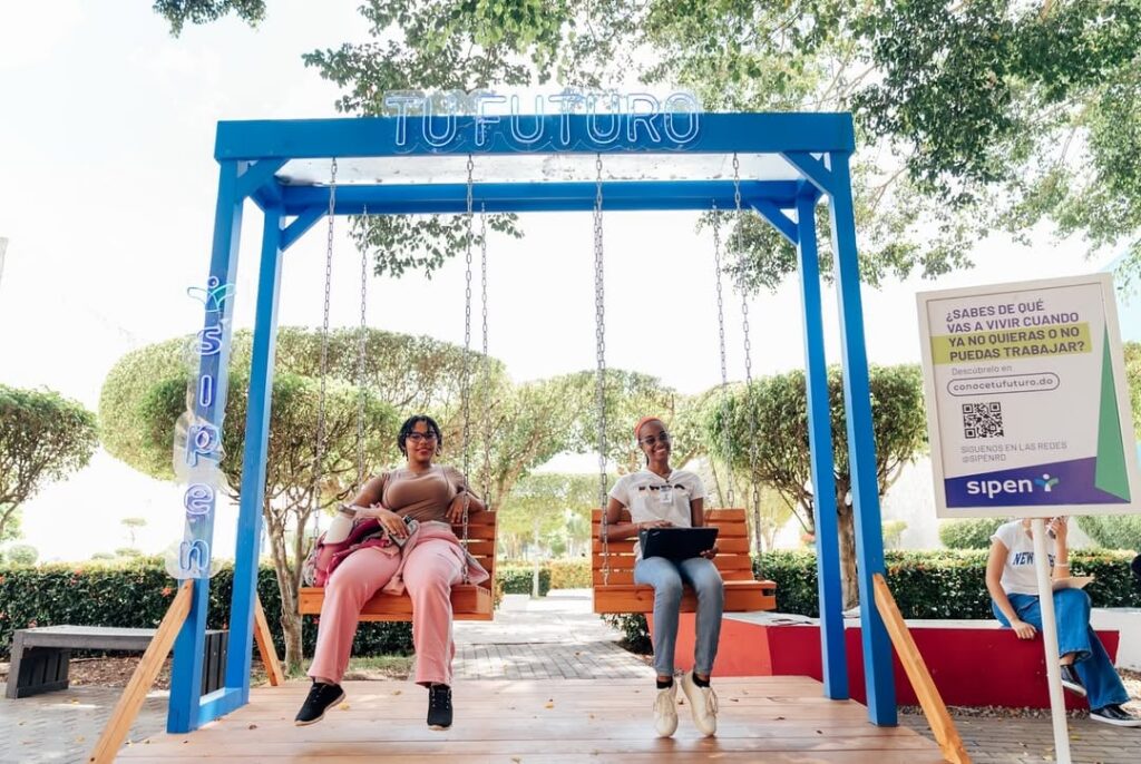 Dos estudiantes se columpian en el parque del ITLA durante la Jornada Vocacional, en un ambiente de recreación y orientación académica.